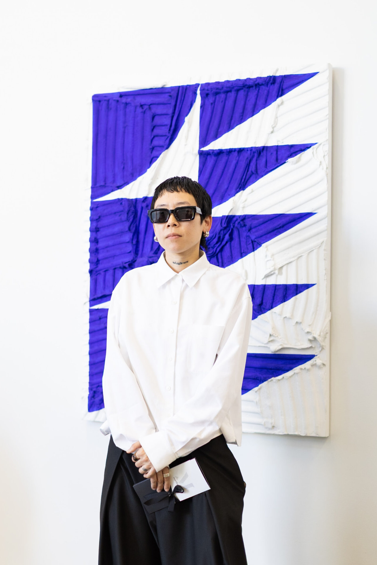 Michelle Jane Lee standing in front of a blue and white relief painting at Quiet Correction I